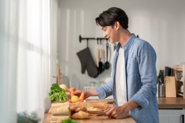 Asyalı yakışıklı adam evde tek başına fırın yapıyor. Çekici erkek fırıncı kendini mutlu ve rahat hisseder, boş zamanlarını evde sağlıklı kahvaltı için yemek pişirerek geçirir..
