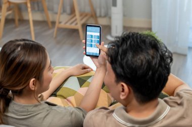 Genç Asyalı çift evde akıllı telefon kullanıyor.