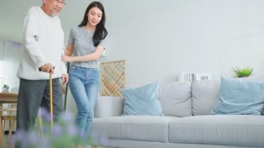 Oturma odasında yaşlı bir adama yardım eden kadın.