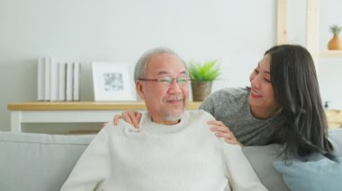 Gülümseyen yaşlı adam genç bir yetişkinle oturuyor.