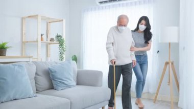 Genç bir kadın içeride bastonlu yaşlı bir adama yardım ediyor..