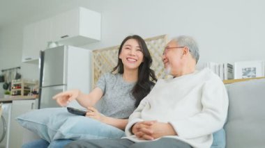 Genç bir kadın içeride yaşlı bir adamla gülüyor.