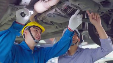 İki Asyalı bir garajda aracın altını inceliyor..