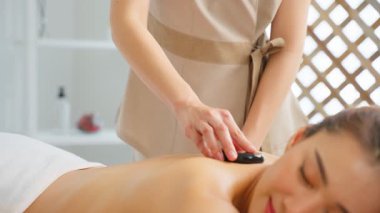 Kadın taşlarla masaj terapisi görüyor.