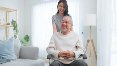 Kadın tekerlekli sandalyedeki yaşlı adamı içeri itiyor.