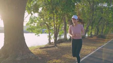 Halk parkında koşan Asyalı genç ve güzel spor kadın..