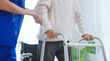 Hemşire içeride yürüyen yaşlı bir adama yardım ediyor..