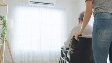 Kadın tekerlekli sandalyedeki yaşlı adamı içeri itiyor.