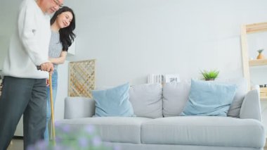 Genç bir kadın içeride bastonlu yaşlı bir adama yardım ediyor..