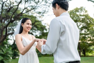 Asyalı romantik evli çift gün batımında parkta birbirine bakıyor. Çekici genç damat ve gelin aşklarını kutluyor ve Sevgililer Günü 'nü dışarıda düğün öncesi fotoğraf çekimlerinin keyfini çıkarıyorlar..