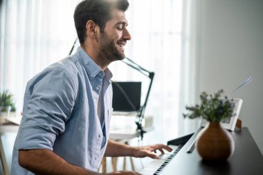Kafkasyalı genç adam piyano çalıyor ve evde elektronik film müzikleri yapıyor. Müzik stüdyosundaki Midi piyano ve ses ekipmanları üzerine yeni bir şarkı besteleyen çekici erkek müzisyen.