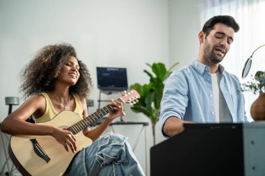 Asyalı bir arkadaşım gitar çalıyor ve evde elektronik film müzikleri yapıyor. Müzik stüdyosunda müzik aleti ve ses ekipmanı kullanarak yeni bir şarkı besteleyen çekici genç müzisyen..