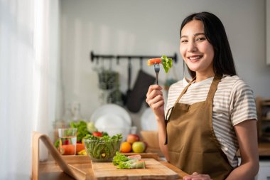 Evdeki mutfakta Vietnam böreği yiyen kadın portresi. Önlük giyen çekici, güzel bir kız. Sabahları evdeki sağlık için temiz aperatifler yiyor. Diyet ve Sağlıklı Yemek Konsepti