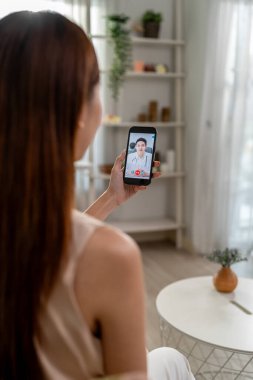 Asyalı genç bayan hasta internette doktorla konuşuyor. Çekici bir doktor, tele sağlık teletıp videosu çekiyor. Evdeki hasta kıza internet danışmanlığı tanısı konuyor..