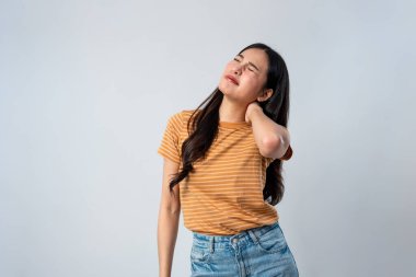 Asyalı genç kadın, izole edilmiş gri arka planda boyun ağrısından muzdarip. Çekici mutsuz genç kız model. Stüdyo çekimlerinde boyun ağrısı ve sağlık sorunları yüzünden stres altında..
