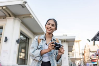Şehirde gezen Asyalı genç bir sırt çantasının portresi. Çekici bayan turist tatil gezisi sırasında sokaklarda boş vakitlerini geçirir ve gülümser ve kameraya bakar.