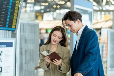 İş adamı ve kadın havaalanındaki uçuş çizelgesini kontrol ediyorlar. Çekici erkek ve kadın yolcular yurtdışına iş için gitmek için heyecanlı ve mutlu hissediyorlar..