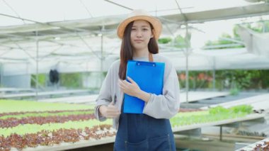 Seradaki bitkileri inceleyen Asyalı kadın..