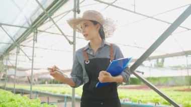 Seradaki bitkileri inceleyen Asyalı kadın..