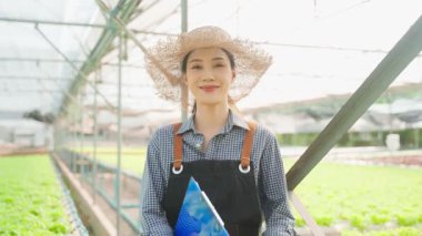 Asyalı genç ve güzel kadın çiftçi sebze çiftliğinde çalışıyor. Tarım sektörü kavramı.