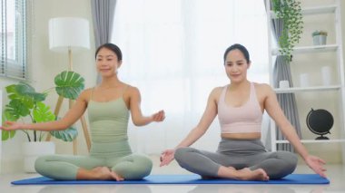 Asyalı kadınlar yoga yapıyor, meditasyon yapıyor, paspasın üzerinde gülümsüyor..