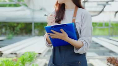 Asyalı genç ve güzel kadın çiftçi sebze çiftliğinde çalışıyor. Tarım sektörü kavramı.