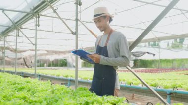 Seradaki bitkileri inceleyen Asyalı bir adam..