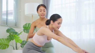 İki kadın kapalı bir stüdyoda yoga yapıyor.