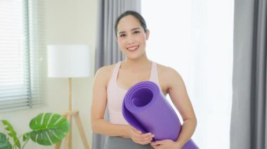 Mor yoga minderi tutan Asyalı genç mutlu kadın..