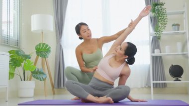 İki kadın kapalı bir stüdyoda yoga yapıyor.
