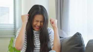 Genç Asyalı kadın bağırıyor, yumruklarını sıkıyor, gözleri kapalı..