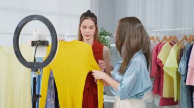 Yaratıcı bir stüdyoda birlikte çalışan iki genç Asyalı moda profesyoneli, konsantre bir ifadeyle bir makyaj ve giysi koleksiyonunu inceliyorlar..