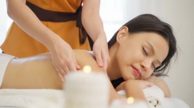 Genç Asyalı kadın güzellik salonunda sırt masajı yaptırıyor.