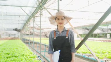 Seradaki bitkileri inceleyen Asyalı kadın..