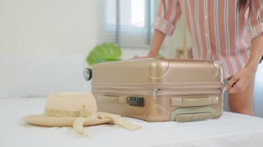 Genç bir kadın valizini topluyor ve şapkasını alıyor, yolculuk için hazır.
