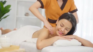 Genç Asyalı kadın güzellik salonunda sırt masajı yaptırıyor.