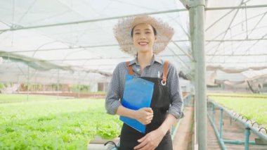 Seradaki bitkileri inceleyen Asyalı kadın..