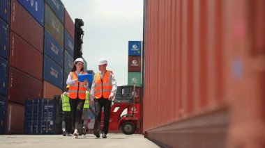 Konteynır terminalinde çalışan beyaz iş adamı ve kadın işçiler. Çekici mühendisler limandaki ithalat ihracatı için kargo nakliye gemisindeki depo lojistiğinde siparişleri ve ürünleri işlerler..