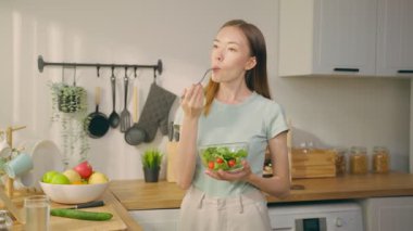 Kadın mutfakta taze salata yiyor.