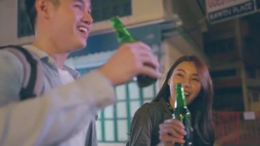 Asyalı kadın tezahürat yapıyor. Elinde yeşil bira şişeleriyle gülüyor..