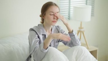 Genç bir kadın yatakta yorgun görünüyor..
