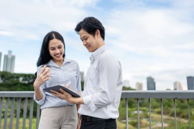 Asyalı genç iş adamı ve kadın ortak şehirde dikiliyor. Çekici iş arkadaşları çalışanlar, ofis dışında kendilerine güvenerek vakit geçirirken mutlu ve rahat hissediyorlar..