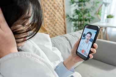 Asyalı genç bayan hasta internette doktorla konuşuyor. Çekici bir doktor, tele sağlık teletıp videosu çekiyor. Evdeki hasta kıza internet danışmanlığı tanısı konuyor..