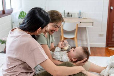 Asyalı lezbiyen çift, erkek çocuklarını evde büyütür ve büyütür. Süt şişesinden bebek besleyen iki kadın, sıcak aile ortamında çocuklarını beslerken hassas anlarını paylaşıyorlar..