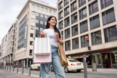 Karışık ırk kadınları alışveriş torbalarını tutarlar ve açık hava pazarında yürürler. Çekici bayan gezgin kendini mutlu ve rahat hissediyor, Frankfurt 'ta tatil gezisi sırasında alışveriş merkezinin dışında eğleniyor..