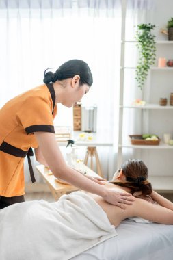 Asyalı genç bir kadın güzellik merkezinde sırt masajı yaptırıyor. Çekici, güzel bir kız masaj yatağında uzanıyor ve masaj salonundaki vücut için masözden rahatlatıcı fizyoterapi hizmeti alıyor.