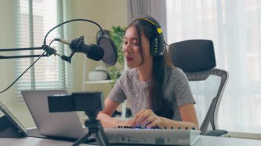 Kapalı mekanda mikrofonla müzik kaydeden genç bir kadın.