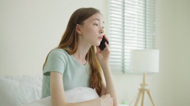 Yatak odasında telefonla konuşan genç bir kadın.