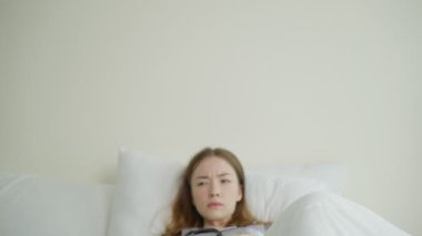 Yatakta yatan genç kadın endişeli görünüyor.