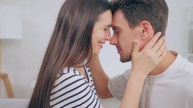 caucasian couple kissing while sitting on the sofa